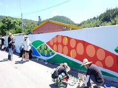 봉사에 참여한 미술동아리 학생들이 한쪽에선 흰벽에 벽화를 그리고 있고, 다른 한쪽에선 페인트통을 만지고 있는 모습