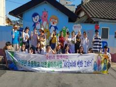 주민과 함께하는 2018년 초등학교 안전울타리사업「사각지대 벽화 그리기」현수막을 든 관계자들이 뽀로로 캐릭터가 그려져 있는 벽화 앞에서 기념 촬영을 하고 있는 모습