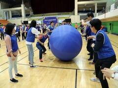 체육관에서 파란색 조끼를 입은 장흥군 공무원들이 파란색 큰 공을 손으로 굴리고 있는 모습