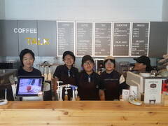 COFFEE TALK라고 명시되어 있는 카페 카운터 앞에 특수교육학생인 여학생 5명이 바리스타 체험을 위해 카페 근무복을 입고 카운터에서 서서 정면을 바라보고 있는 모습