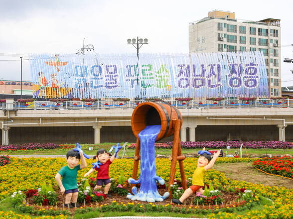 물축제 행사장 사진(조형물 뒤로 화단과 '맑은물 푸른숲 정남진 장흥' 홍보기가 보인다)