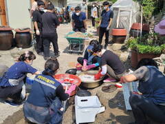 정남진사랑나눔봉사대 25일 유치면서 11개 분야 봉사활동 진행 - 자원봉사자들이 마당의 쓰레기를 정리하고 마당 오른쪽 수도에서는 생할식기를 설겆이하고있다.