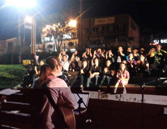 달구지 콘서트 관객들 앞에서 가수가 노래를 부르고 있는 모습