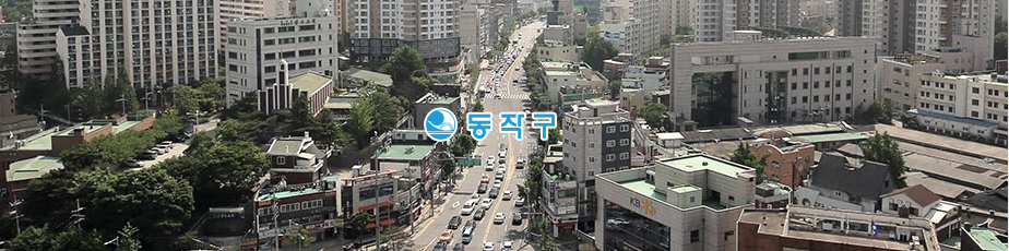 (동작구) 로고가 표기되어 있고, 회색빛 건물들이 모여있고 가운데 6차선 도로에 차들이 이동하는 동작구의 모습