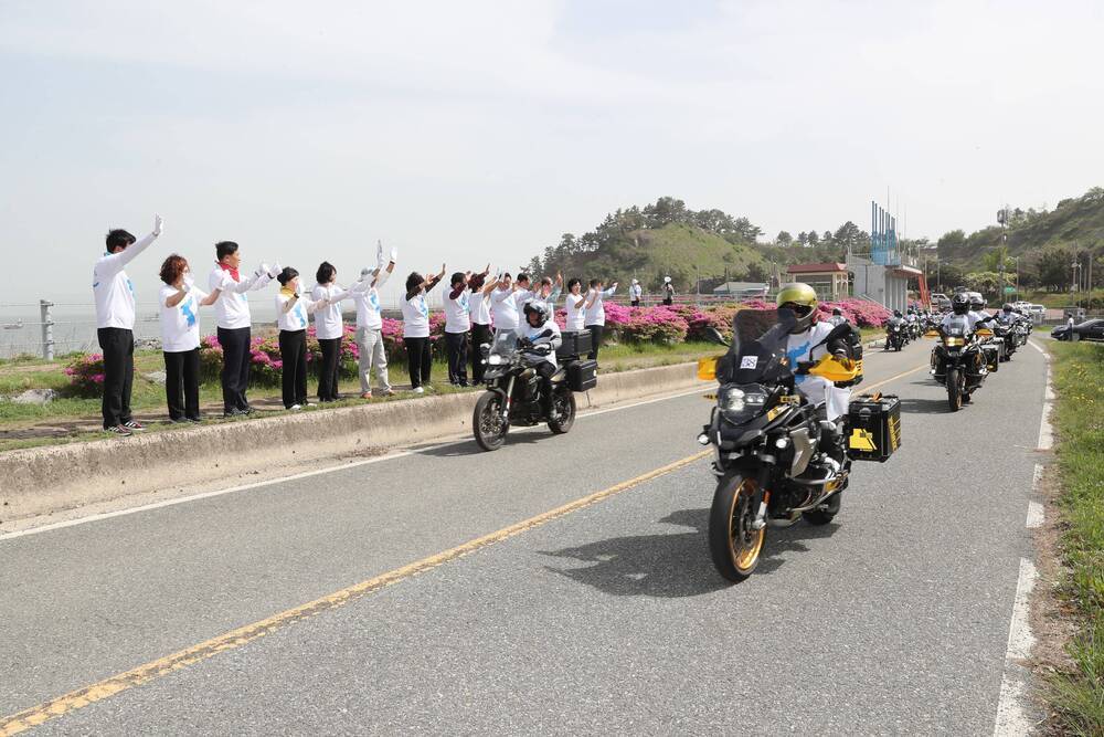 통일기원 퍼레이드중인 오토바이 행렬과 길가에서 손을 흔들고 있는 군민들 사진